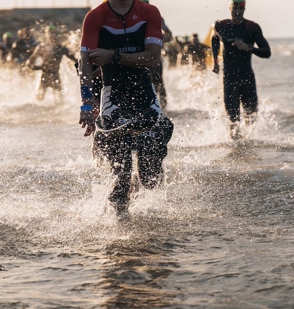 Triathlète en maillot Pla3Coach’In en sortie d’eau au lever du jour, éclaboussures